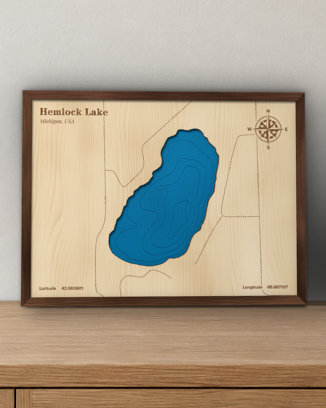 Hemlock Lake wood map in a walnut frame standing on a wooden sideboard against a wall for scale