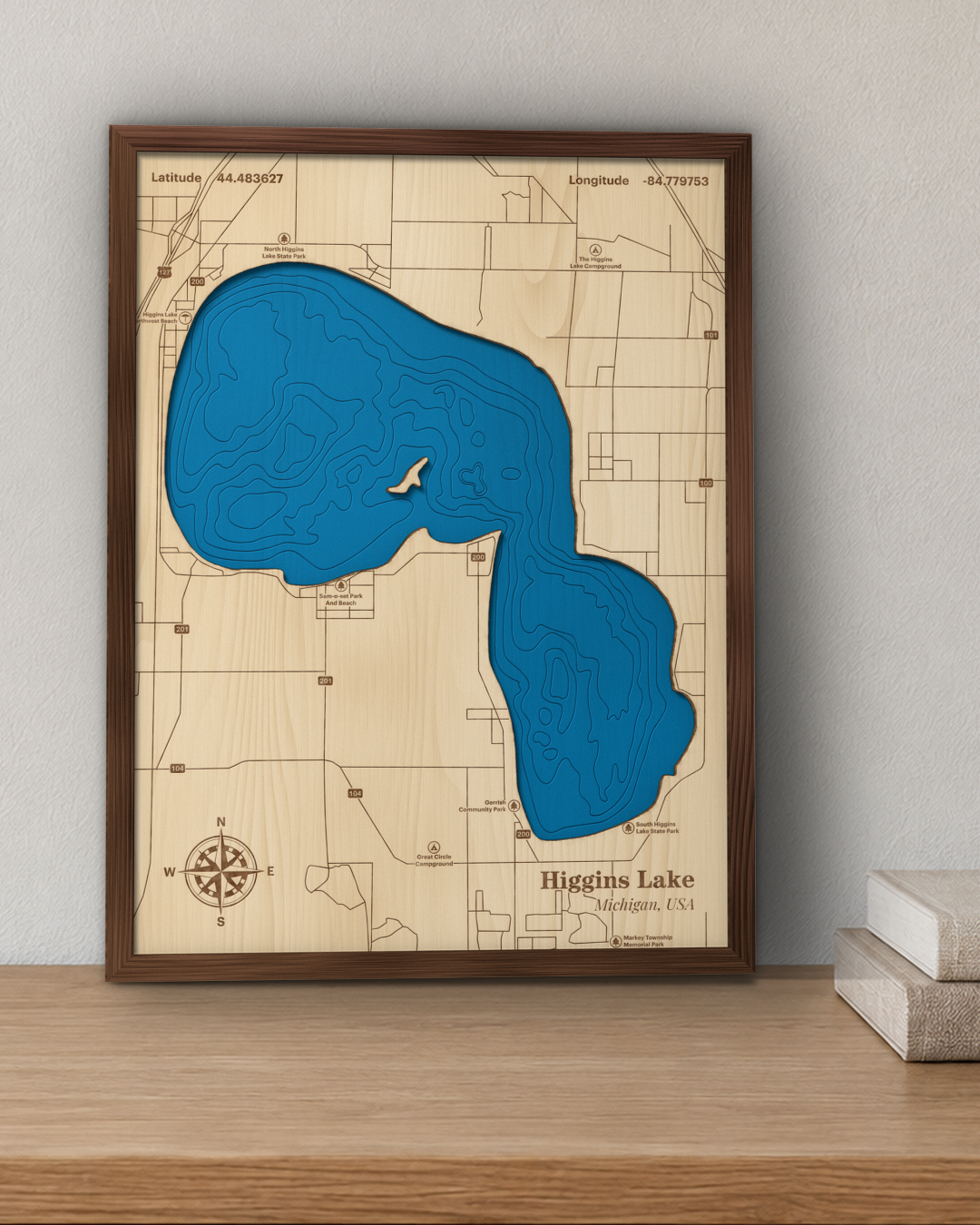 Higgins Lake wood map in a walnut frame standing on a wooden sideboard against a wall for scale