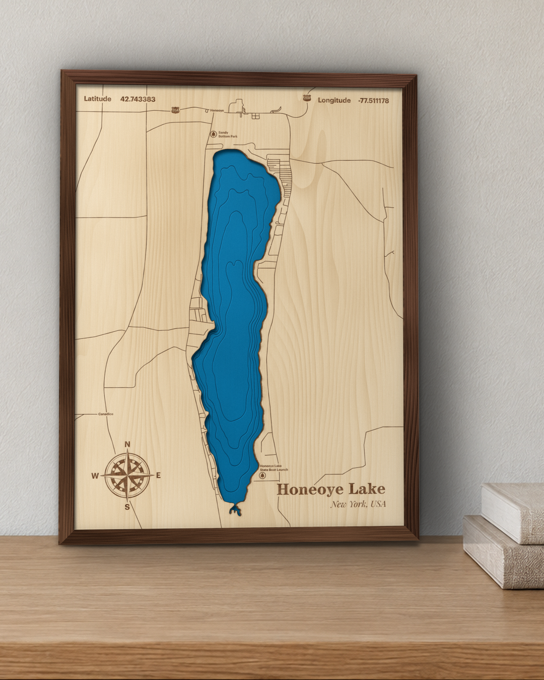 Honeoye Lake wood map in a walnut frame standing on a wooden sideboard against a wall for scale