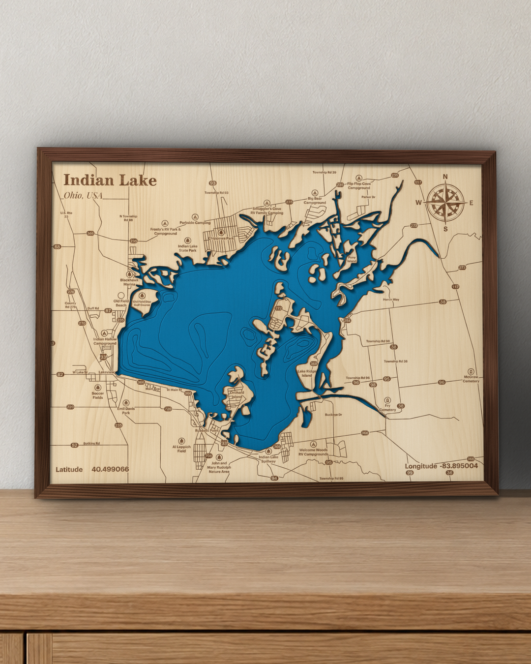 Indian Lake wood map in a walnut frame standing on a wooden sideboard against a wall for scale