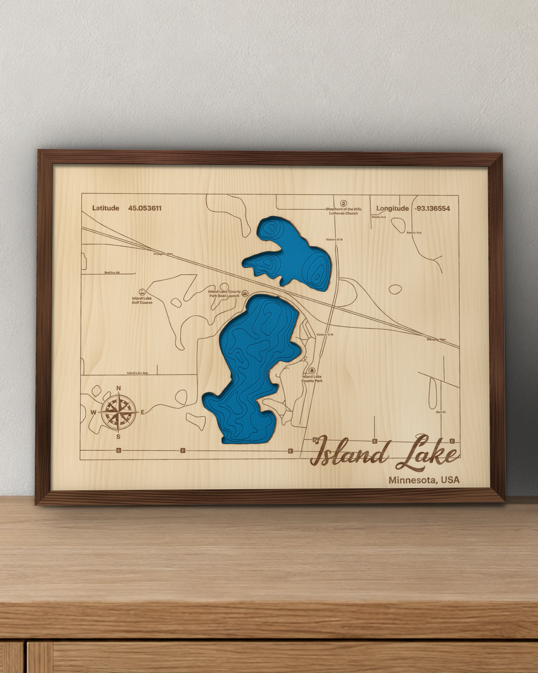 Island Lake wood map in a walnut frame standing on a wooden sideboard against a wall for scale