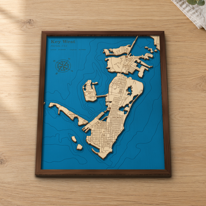 Key West wood map lying flat on a wooden tabletop, showing the island's street grid, Stock Island and the surrounding depth contours