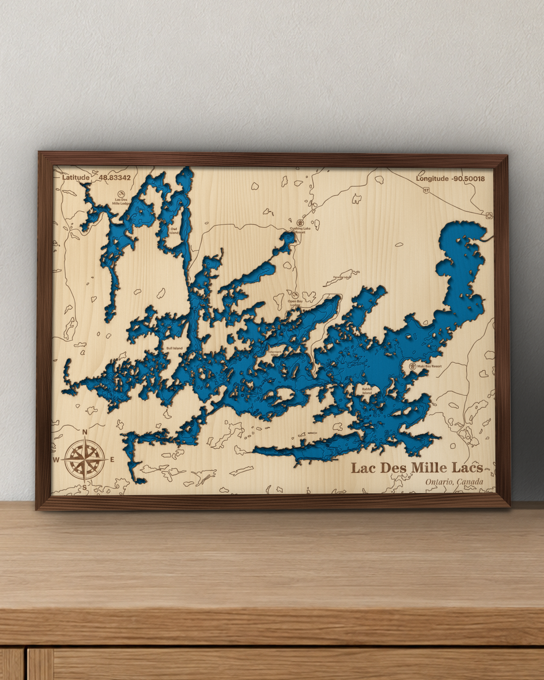 Lac des Mille Lacs wood map in a walnut frame standing on a wooden sideboard against a wall for scale