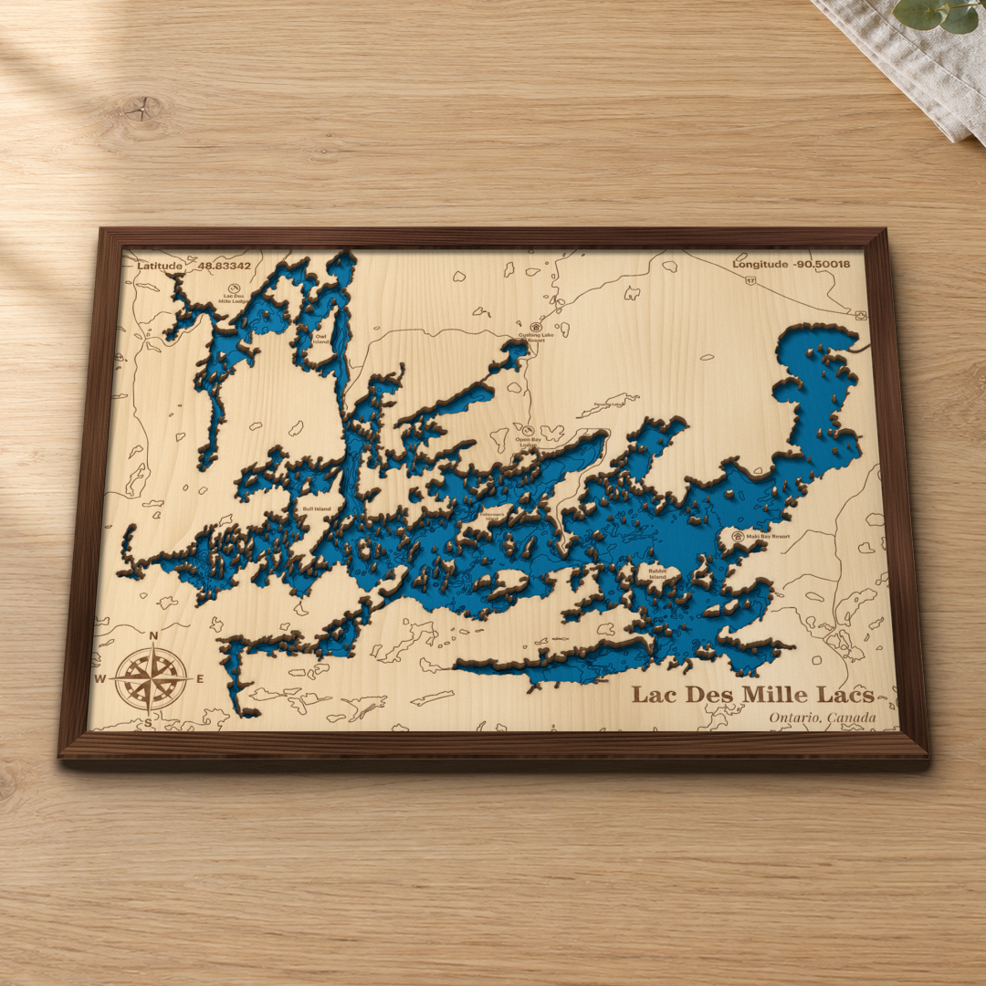 Lac des Mille Lacs wood map lying flat on a wooden tabletop, showing the depth contours, the islands and the lodges engraved in