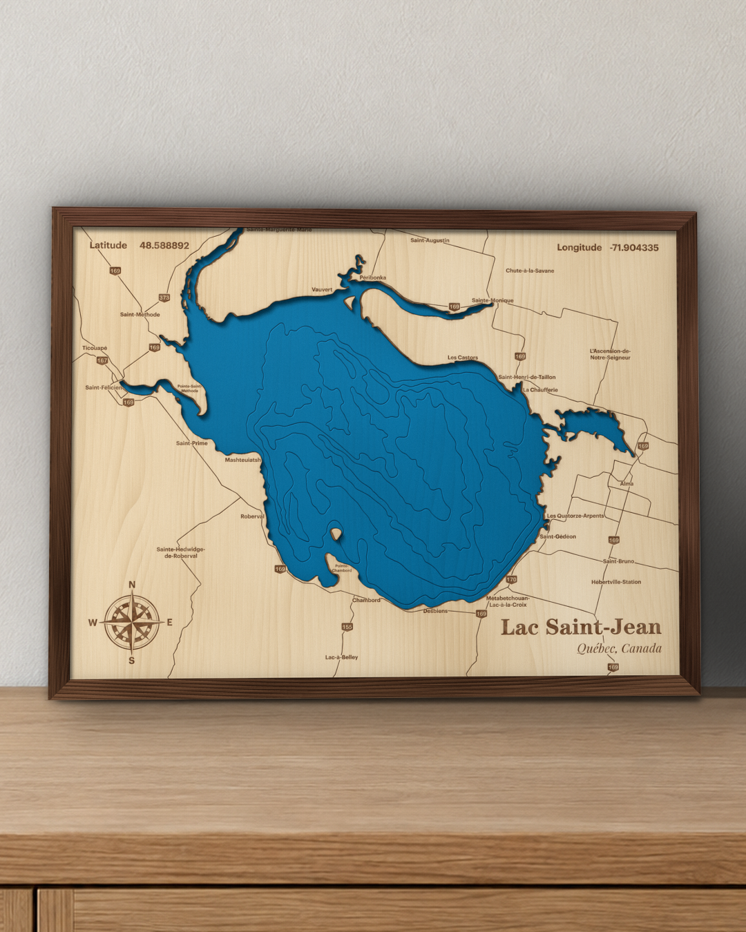 Lac Saint-Jean wood map in a walnut frame standing on a wooden sideboard against a wall for scale