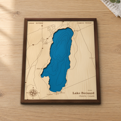 Lake Bernard wood map lying flat on a wooden tabletop, showing the lake's depth contours with Lake Bernard Park, Checkerboard Beach and Highway 11 engraved in