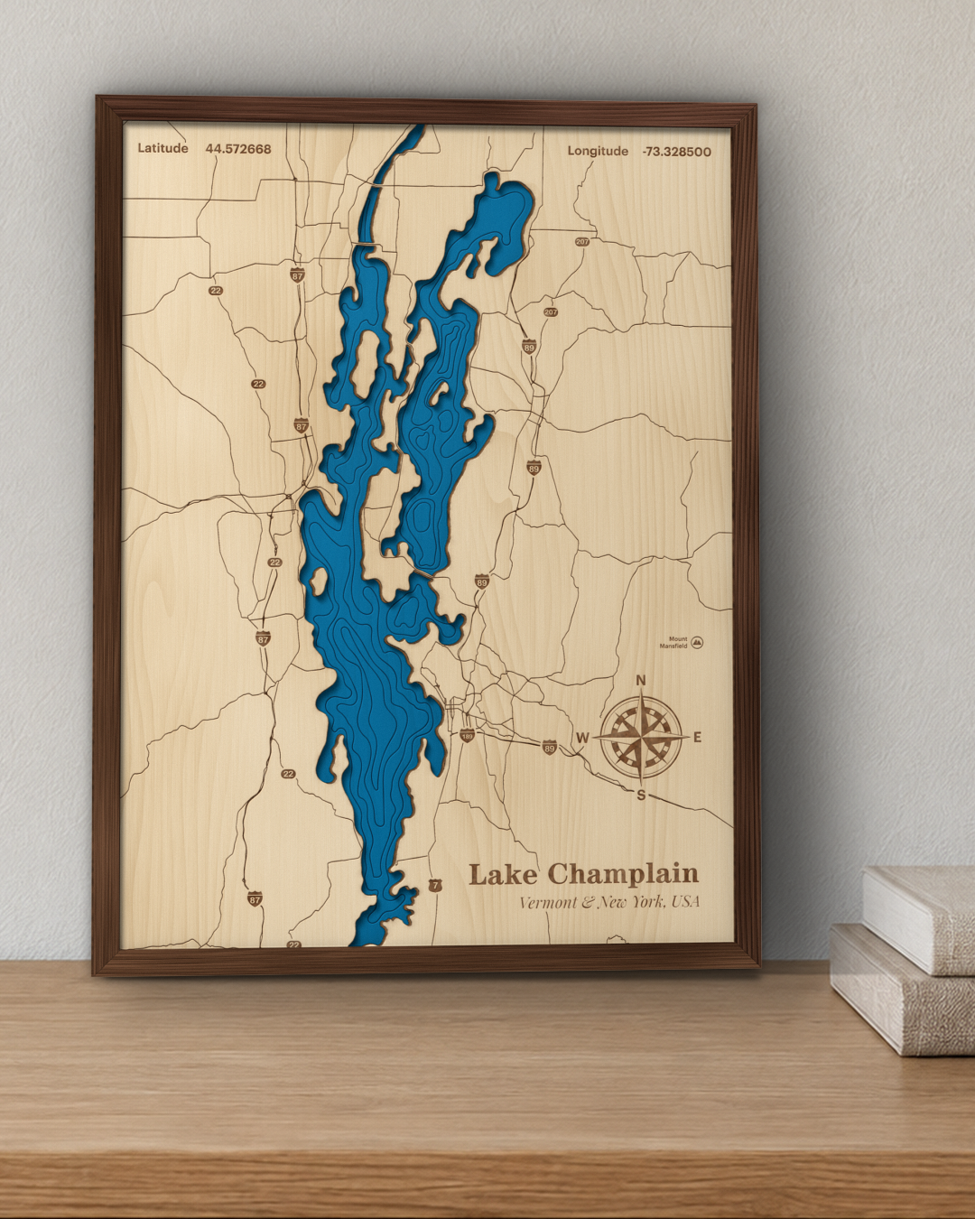 Lake Champlain wood map in a walnut frame standing on a wooden sideboard against a wall for scale