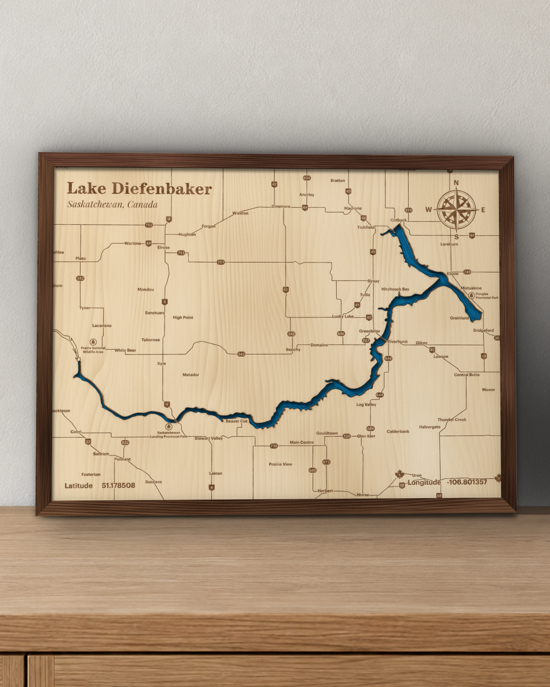 Lake Diefenbaker wood map in a walnut frame standing on a wooden sideboard against a wall for scale