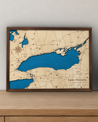 Lake Ontario wood map in a walnut frame standing on a wooden sideboard against a wall for scale