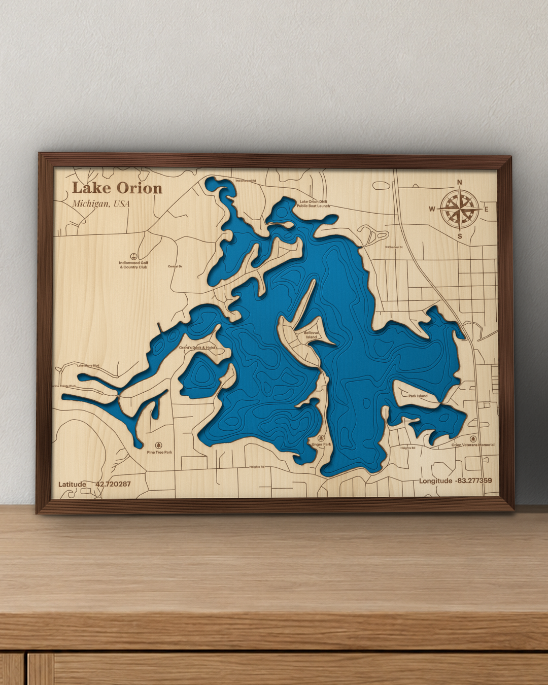 Lake Orion wood map in a walnut frame standing on a wooden sideboard against a wall for scale