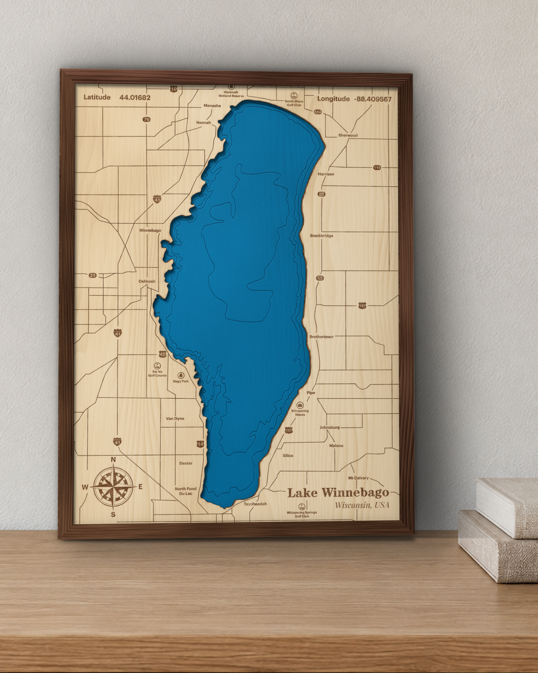 Lake Winnebago wood map in a walnut frame standing on a wooden sideboard against a wall for scale