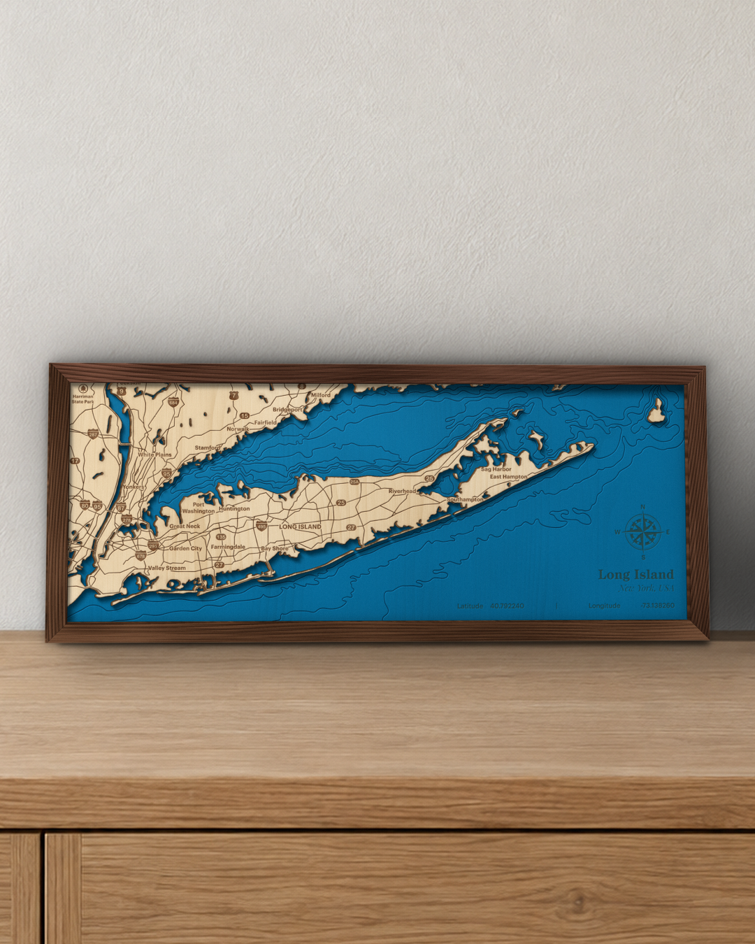 Long Island wood map in a walnut frame standing on a wooden sideboard against a wall for scale