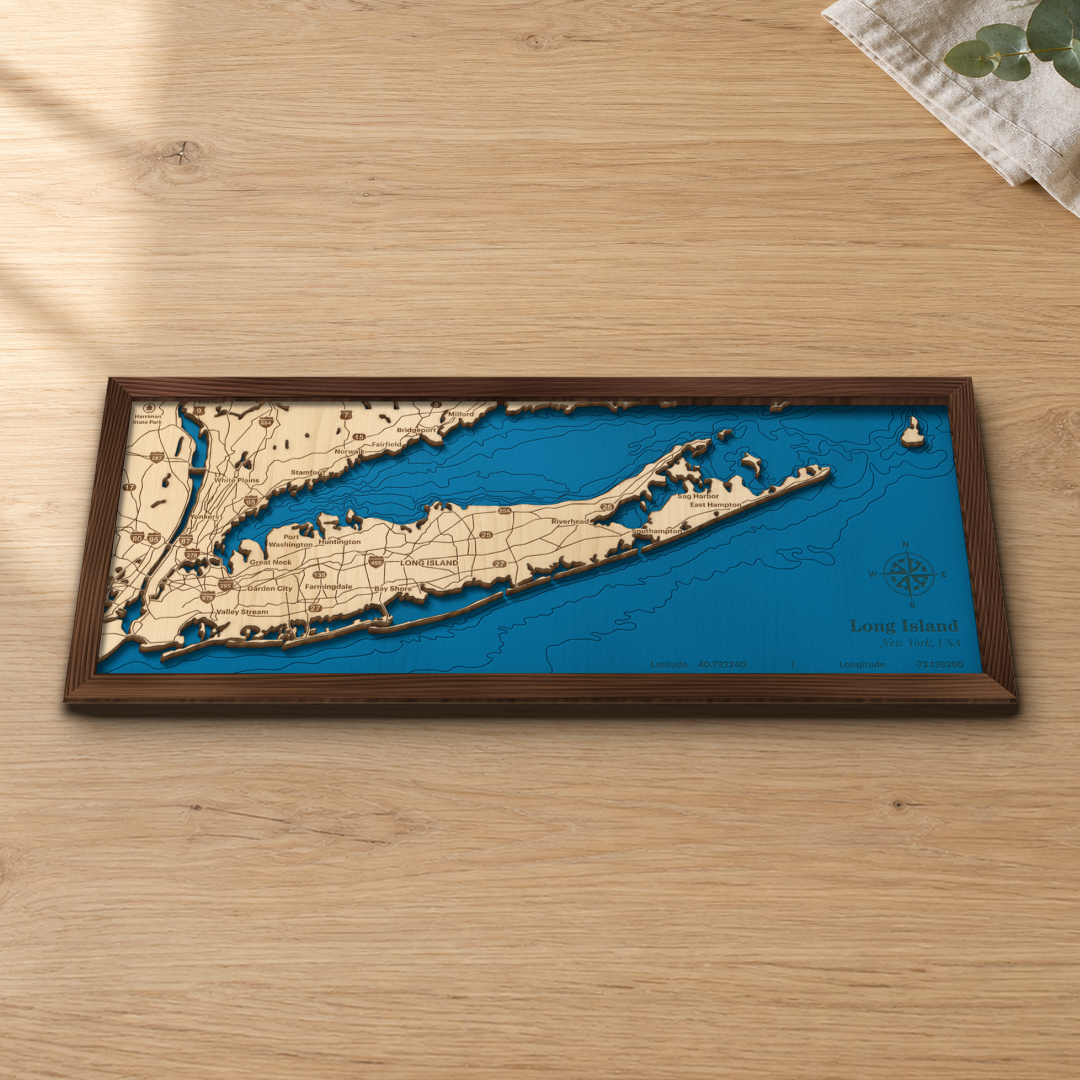 Long Island wood map lying flat on a wooden tabletop, showing the depth contours in Long Island Sound and the Atlantic with engraved towns and highways from Garden City and Huntington to Riverhead, Sag Harbor and East Hampton