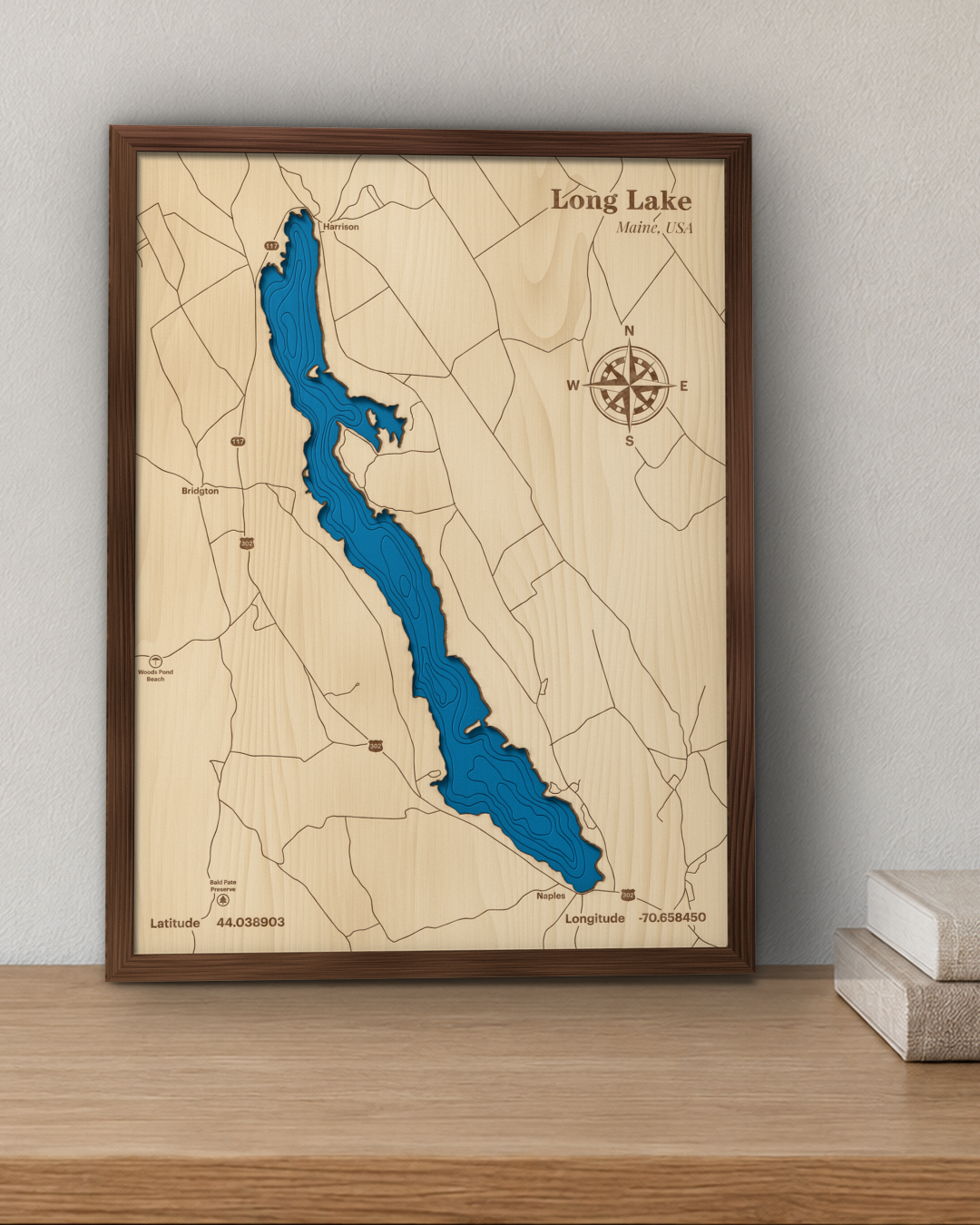 Long Lake wood map in a walnut frame standing on a wooden sideboard against a wall for scale