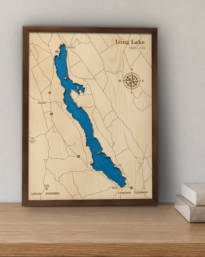 Long Lake wood map in a walnut frame standing on a wooden sideboard against a wall for scale