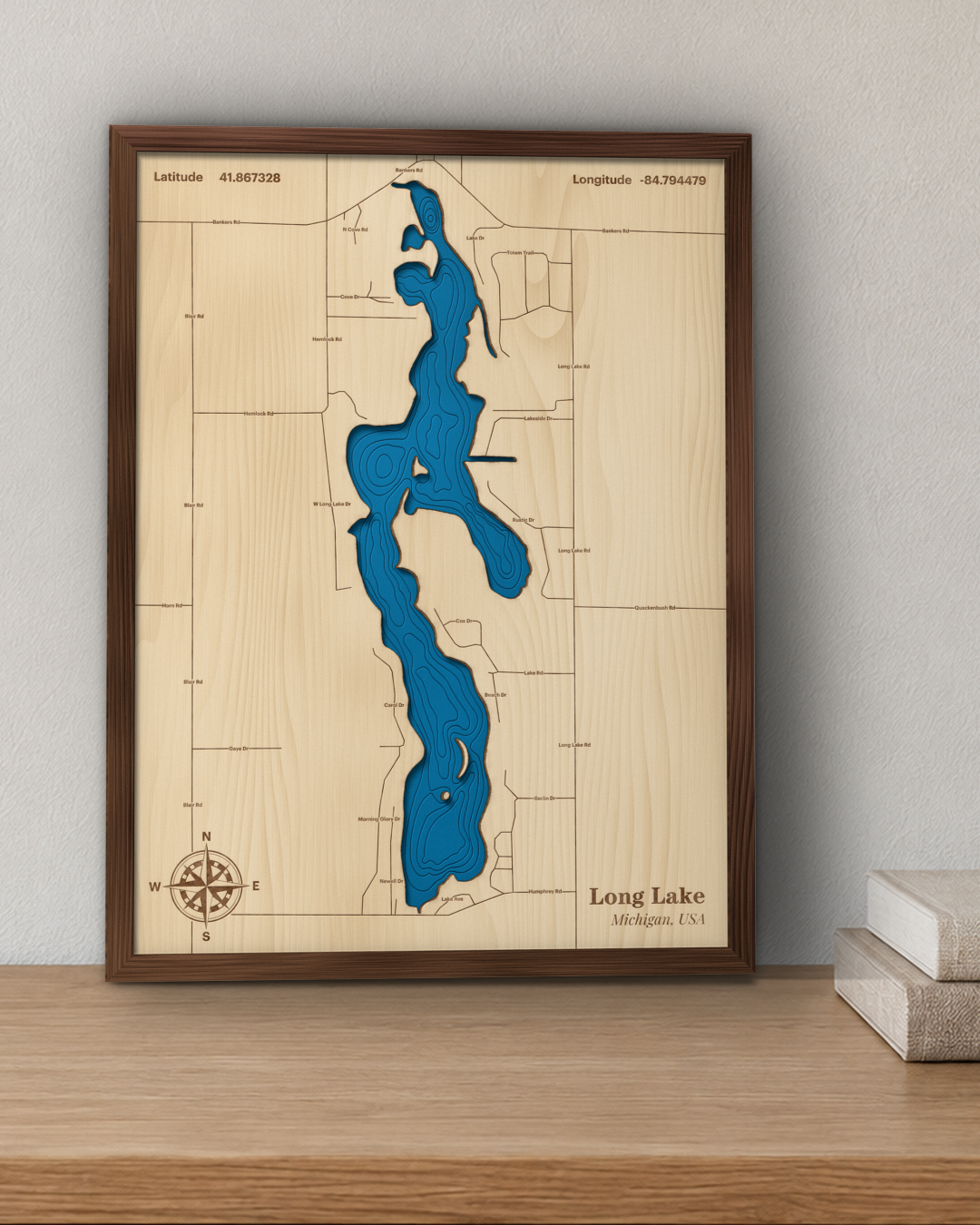 Long Lake wood map in a walnut frame standing on a wooden sideboard against a wall for scale