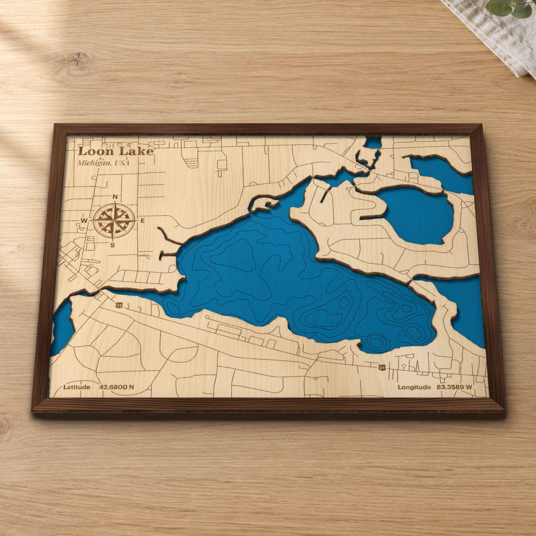 Loon Lake wood map lying flat on a wooden tabletop, showing the lake's depth contours, the neighboring lakes and the roads around its shore