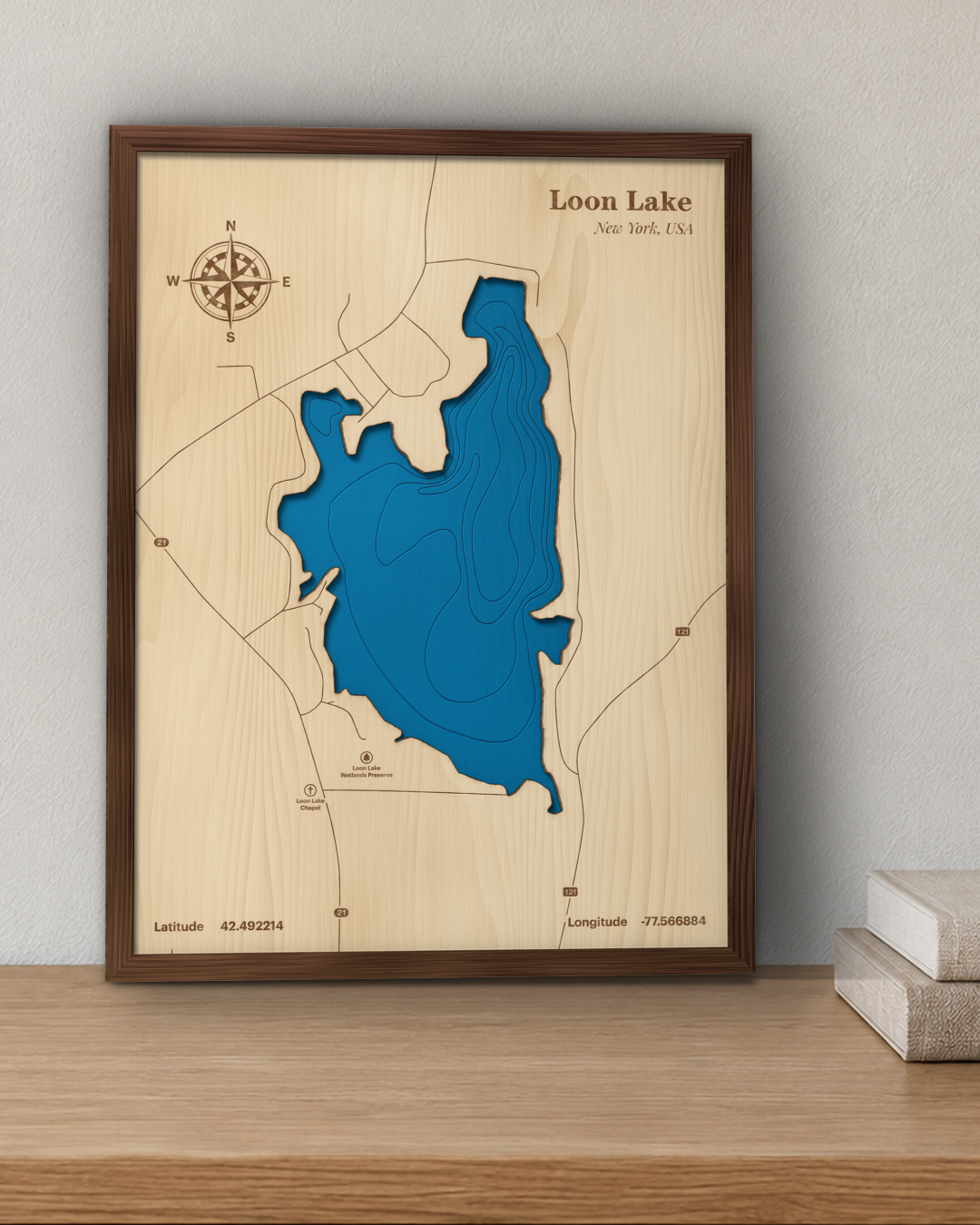 Loon Lake wood map in a walnut frame standing on a wooden sideboard against a wall for scale