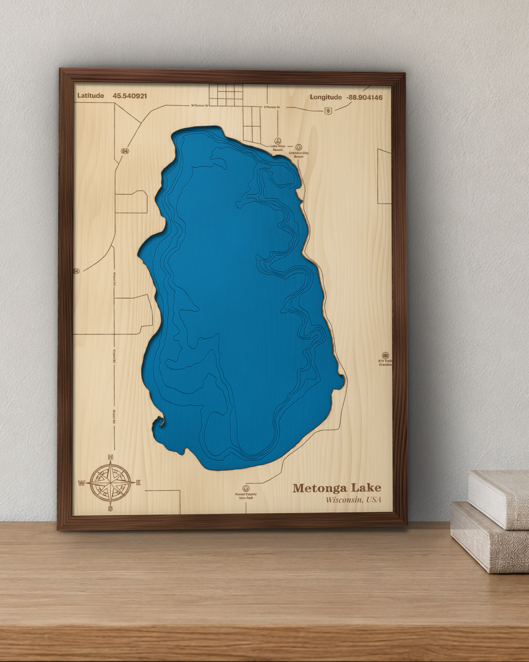 Metonga Lake wood map in a walnut frame standing on a wooden sideboard against a wall for scale