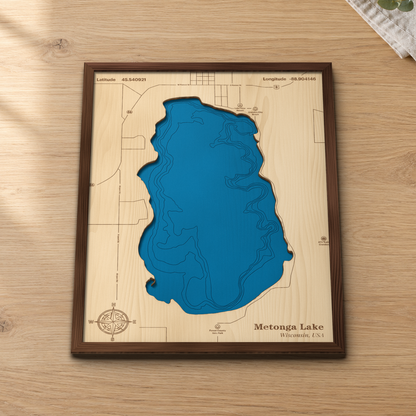 Metonga Lake wood map lying flat on a wooden tabletop, showing the depth contours and the city of Crandon on the north shore engraved in