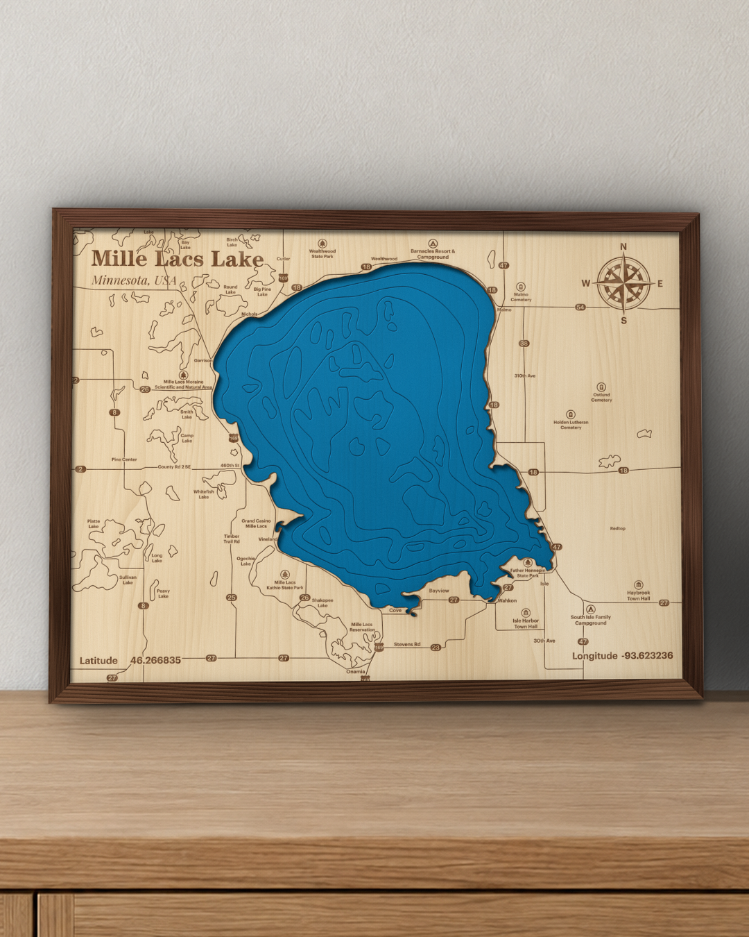 Mille Lacs Lake wood map in a walnut frame standing on a wooden sideboard against a wall for scale