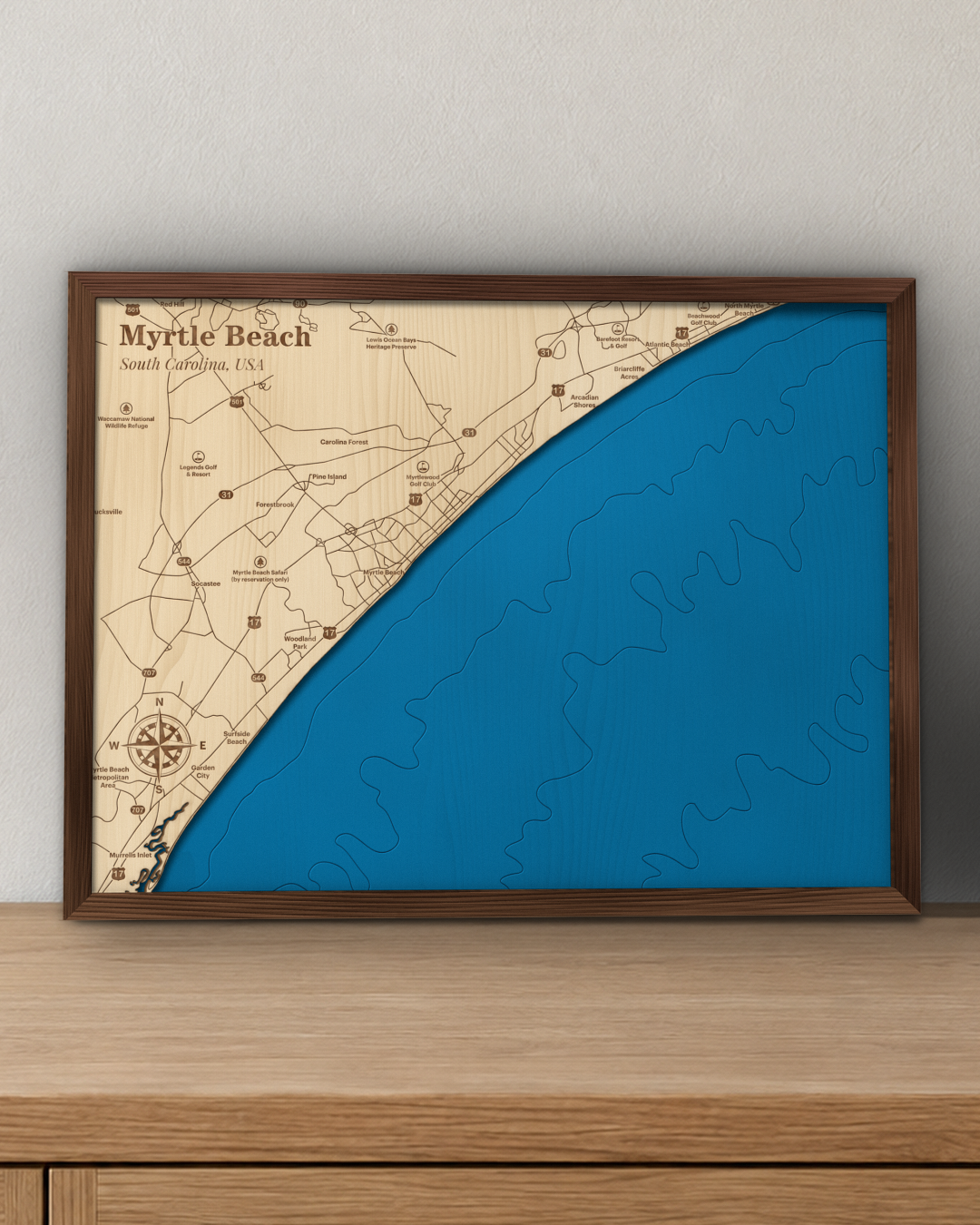 Myrtle Beach wood map in a walnut frame standing on a wooden sideboard against a wall for scale