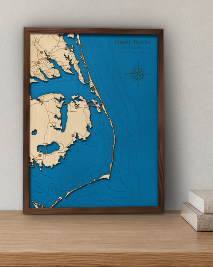 Outer Banks wood map in a walnut frame standing on a wooden sideboard against a wall for scale