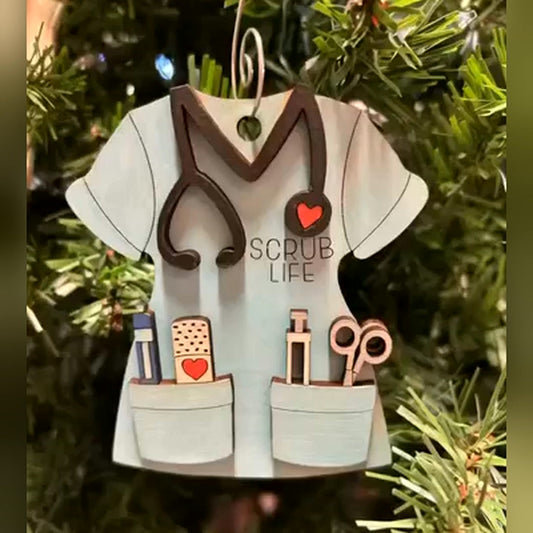 Scrub Life hand-painted wood ornament, light blue scrub top with stethoscope, red heart and pocket tools, hanging on a Christmas tree