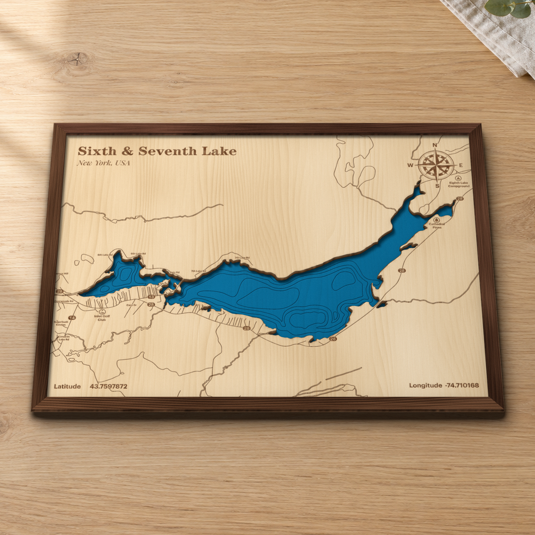 Sixth & Seventh Lake wood map lying flat on a wooden tabletop, showing Sixth and Seventh Lake's depth contours with Route 28, Inlet Golf Club and Eighth Lake Campground engraved in