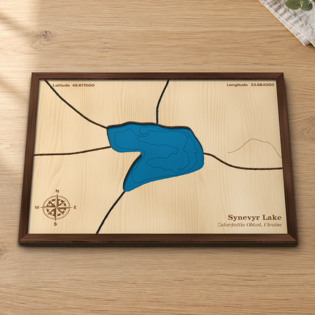 Synevyr Lake wood map lying flat on a wooden tabletop, showing the mountain lake's depth contours and the streams that feed it
