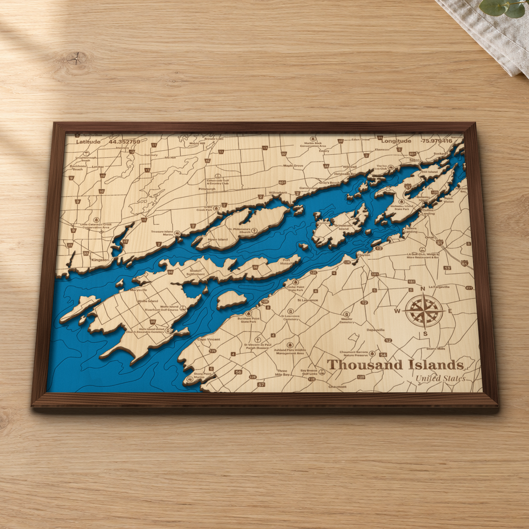 Thousand Islands wood map lying flat on a wooden tabletop, showing the St. Lawrence River's islands and depth contours from Kingston and Wolfe Island to Clayton