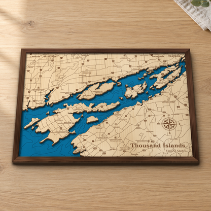 Thousand Islands wood map lying flat on a wooden tabletop, showing the St. Lawrence River's islands and depth contours from Kingston and Wolfe Island to Clayton