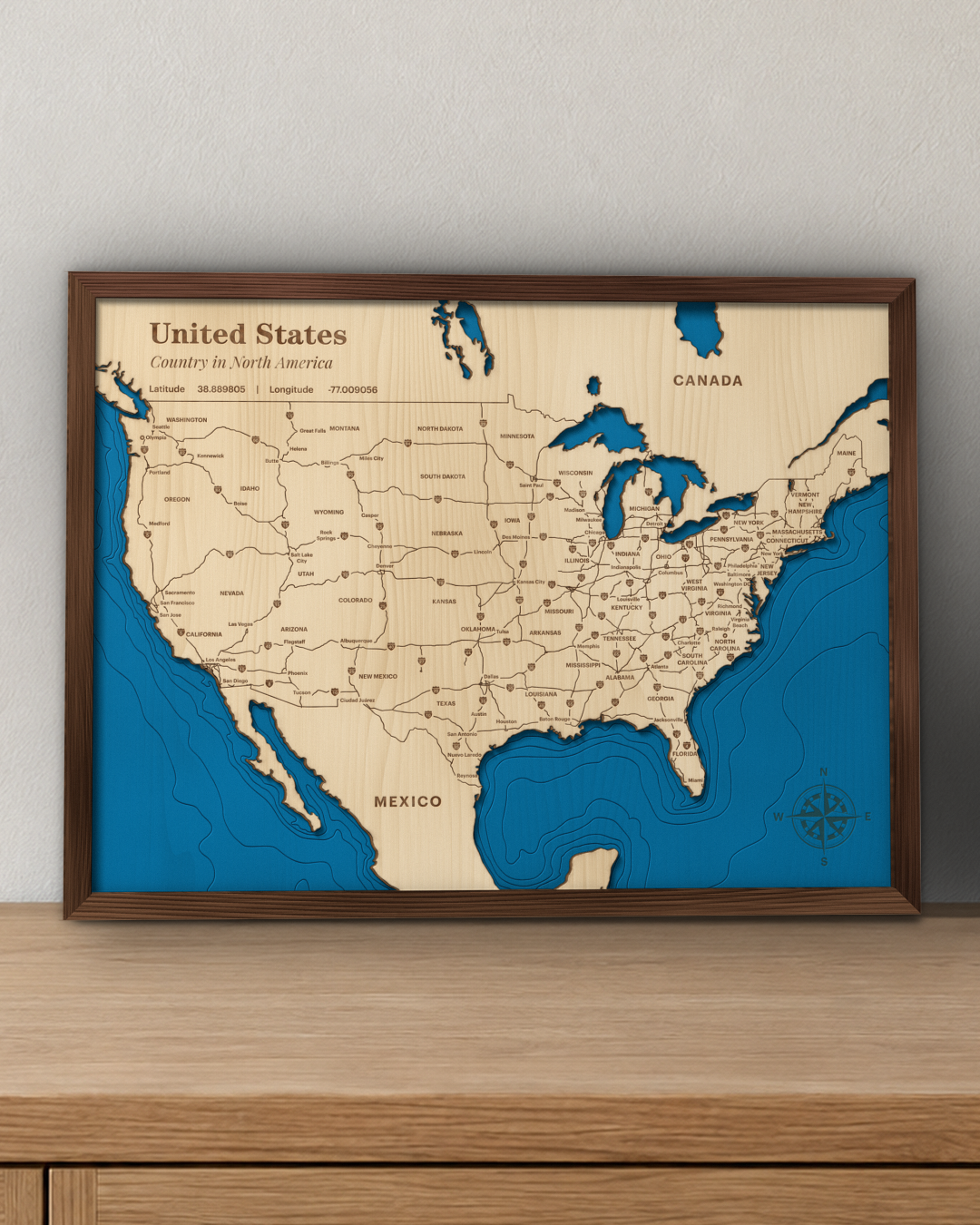 United States wood map in a walnut frame standing on a wooden sideboard against a wall for scale