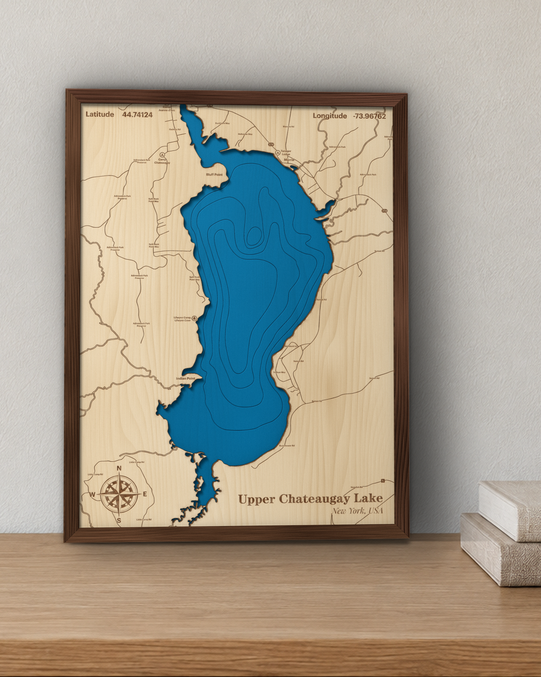 Upper Chateaugay Lake wood map in a walnut frame standing on a wooden sideboard against a wall for scale
