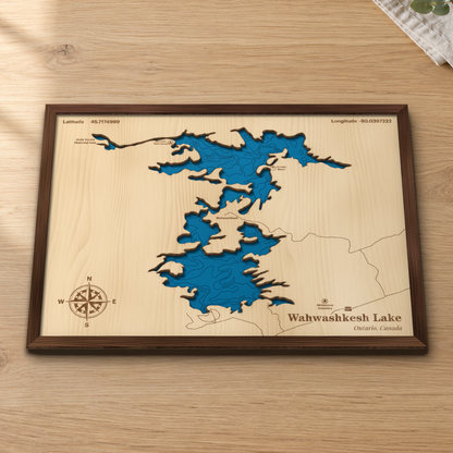 Wahwashkesh Lake wood map lying flat on a wooden tabletop, showing the lake's depth contours across its many bays and inlets, with Morton's Point Camp and Straubs Beach engraved in